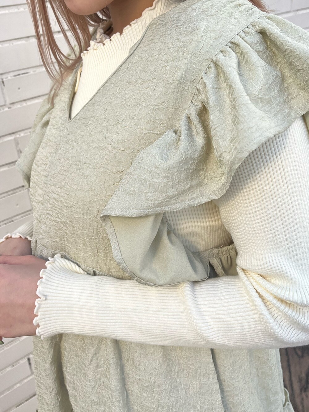 ベージュ系のブーツ、グリーン系のワンピース、ホワイト系のニット/セーターを着用したレディースの冬コーディネートの6枚目の写真