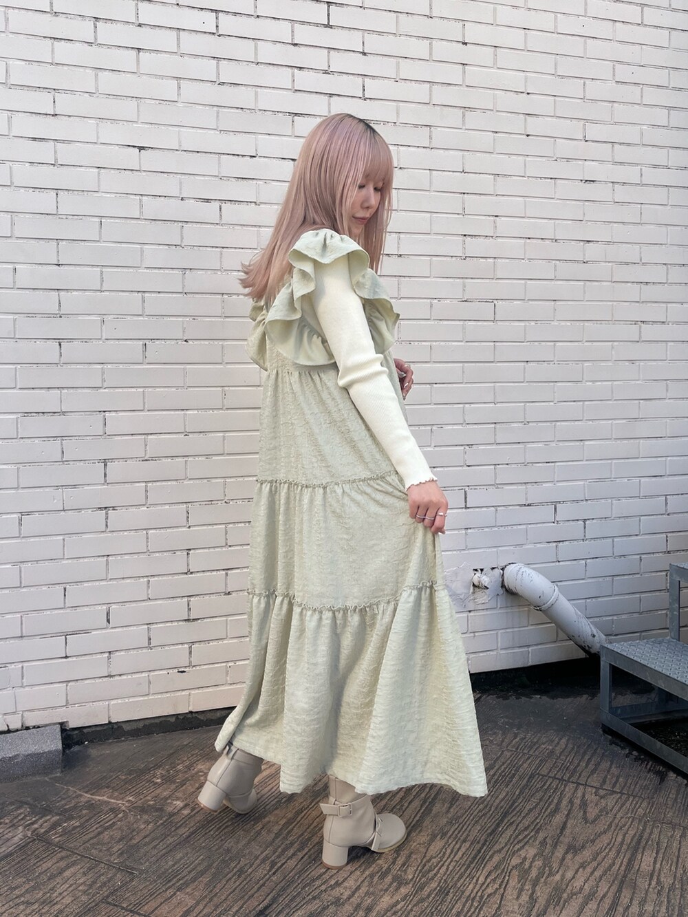 ベージュ系のブーツ、グリーン系のワンピース、ホワイト系のニット/セーターを着用したレディースの冬コーディネートの2枚目の写真