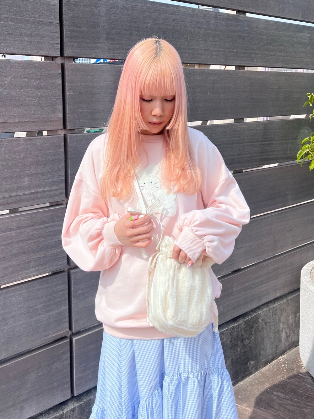 ピンク系のスウェット、ブルー系のスカート、ホワイト系のバレエシューズを着用したレディースの春コーディネートの4枚目の写真