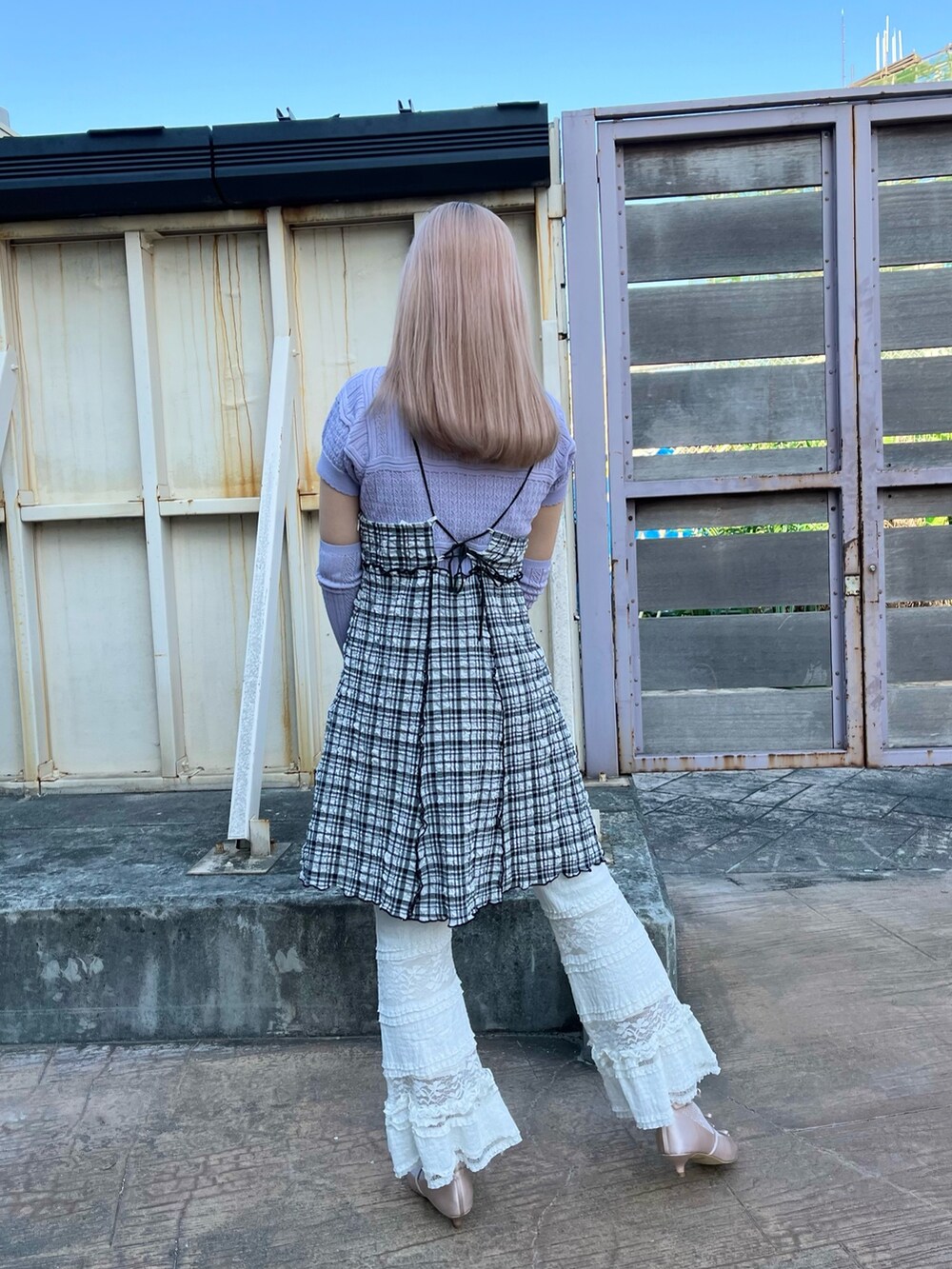 パープル系のニット/セーター、ブラック系のワンピース、ホワイト系のスラックスを着用したレディースの春コーディネートの2枚目の写真