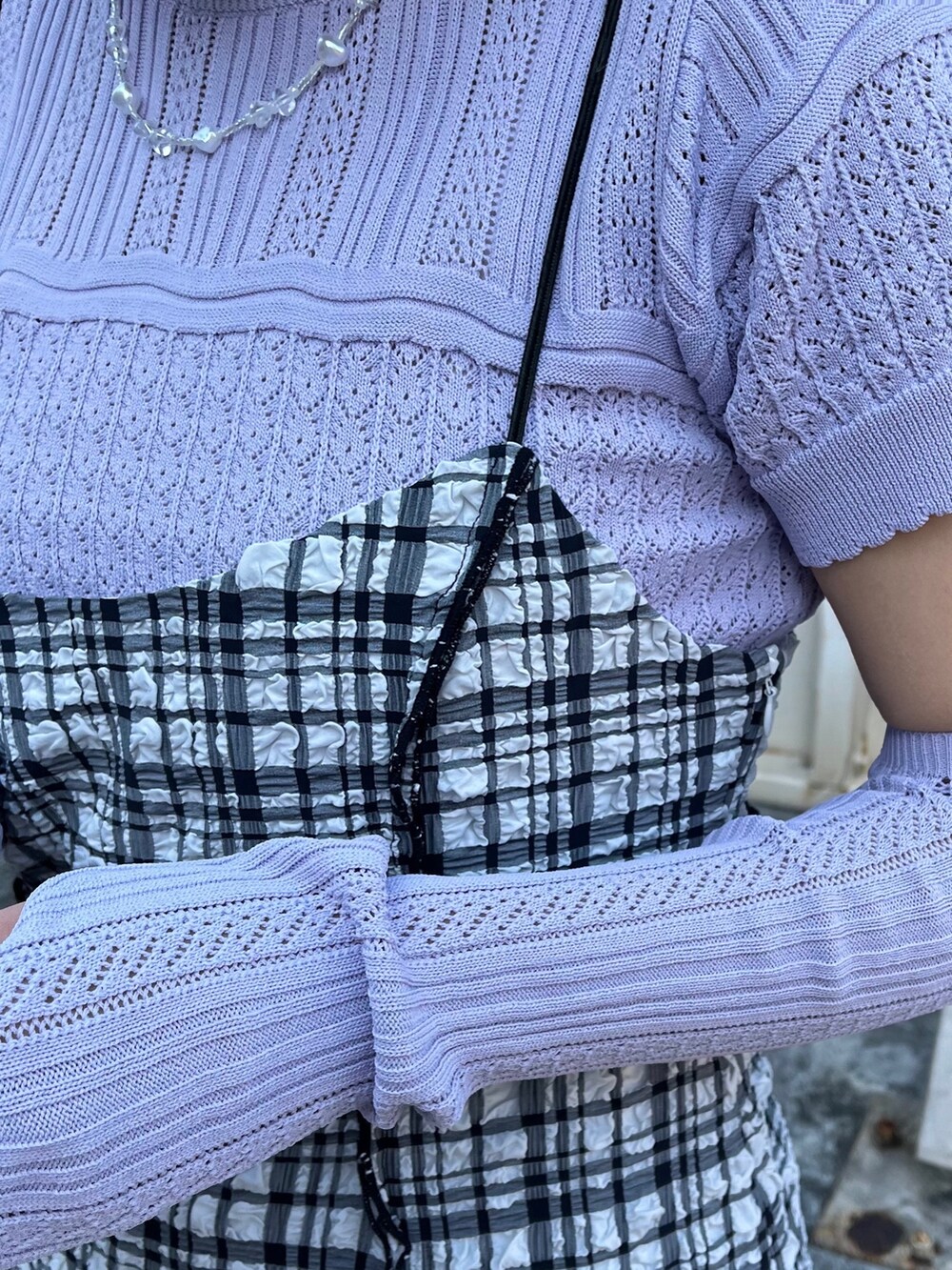 パープル系のニット/セーター、ブラック系のワンピース、ホワイト系のスラックスを着用したレディースの春コーディネートの4枚目の写真