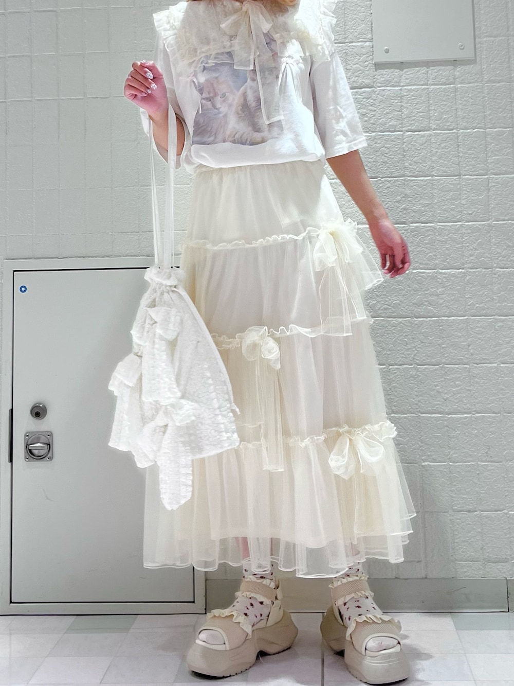 ホワイト系のTシャツ/カットソー、ホワイト系のスカート、ホワイト系のトートバッグを着用したレディースの夏コーディネートの2枚目の写真