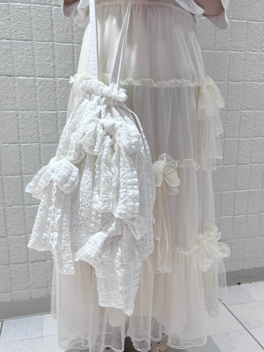 ホワイト系のTシャツ/カットソー、ホワイト系のスカート、ホワイト系のトートバッグを着用したレディースの夏コーディネートの6枚目の写真