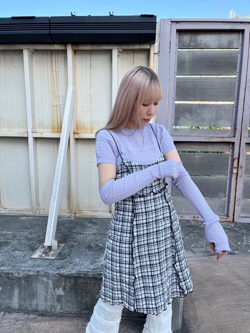 パープル系のニット/セーター、ブラック系のワンピース、ホワイト系のスラックスを着用したレディースの春コーディネートの3枚目の写真