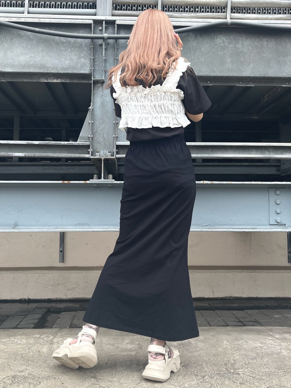 ホワイト系のベスト、グレー系のTシャツ/カットソー、ブラック系のスカートを着用したレディースの春コーディネートの2枚目の写真