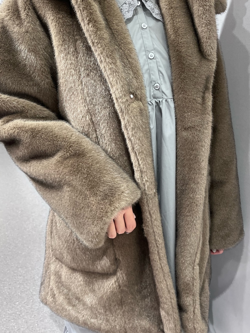 ブラウン系のノーカラーコート、グレー系のワンピース、ブルー系のデニムパンツを着用したレディースの冬コーディネートの7枚目の写真