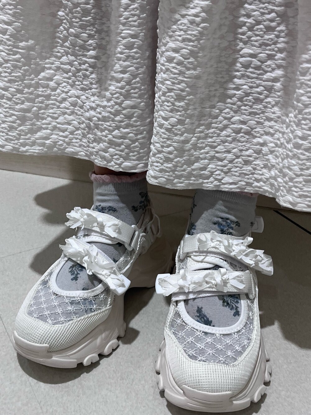 ピンク系のニット/セーター、ホワイト系のキャミソール、ホワイト系のスカートを着用したレディースの冬コーディネートの9枚目の写真