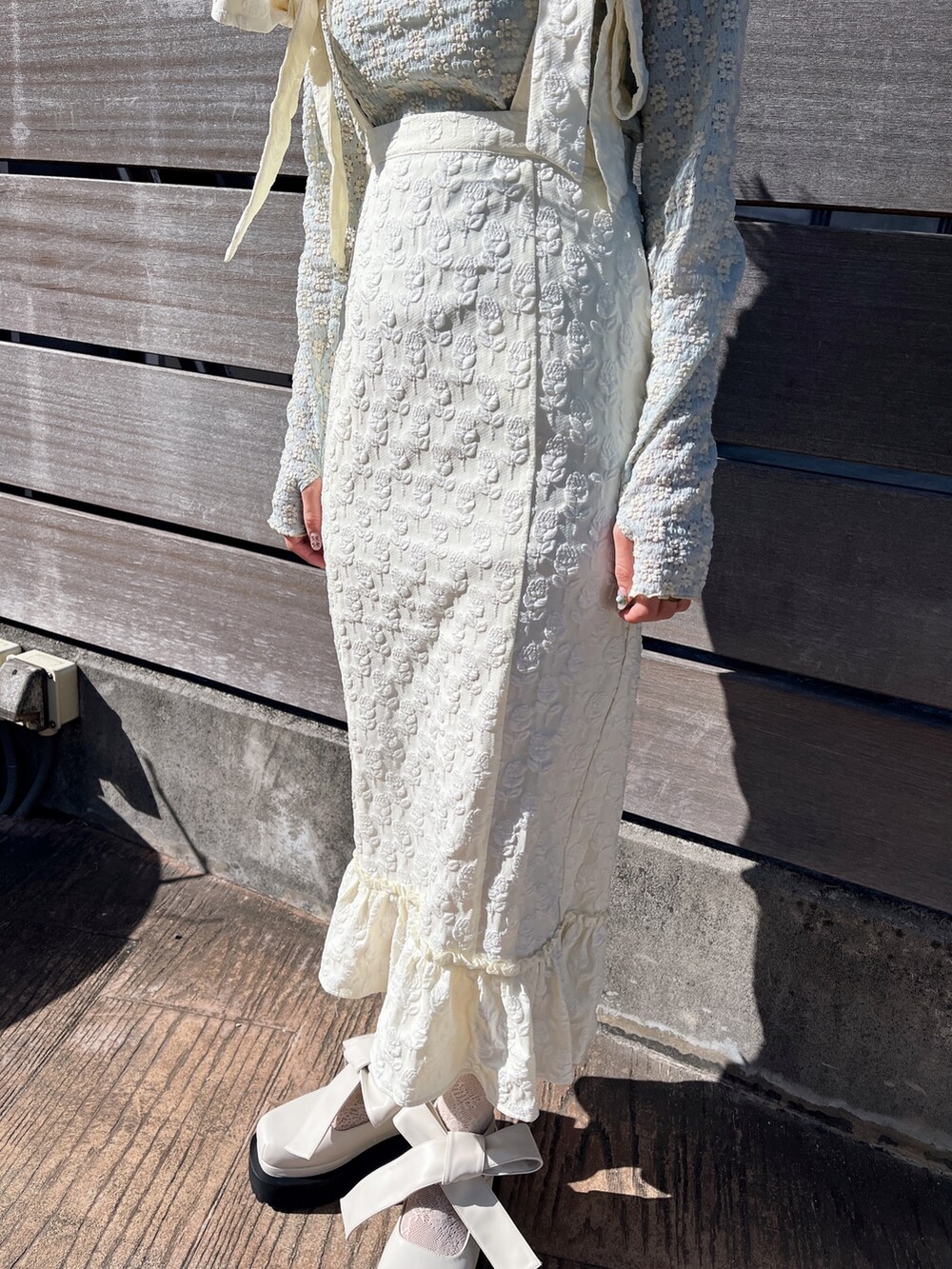 ブルー系のTシャツ/カットソー、ホワイト系のスカート、ホワイト系のパンプスを着用したレディースの冬コーディネートの5枚目の写真