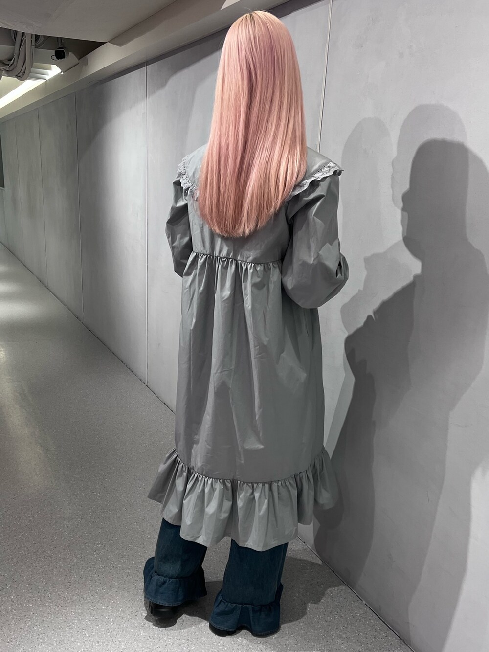 ブラウン系のノーカラーコート、グレー系のワンピース、ブルー系のデニムパンツを着用したレディースの冬コーディネートの4枚目の写真