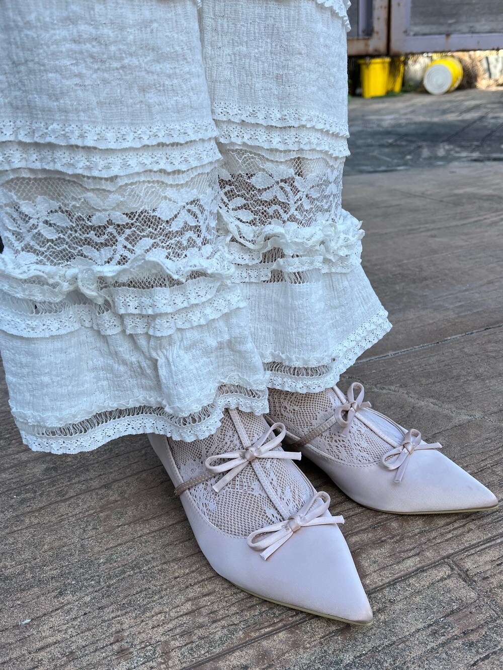 パープル系のニット/セーター、ブラック系のワンピース、ホワイト系のスラックスを着用したレディースの春コーディネートの6枚目の写真