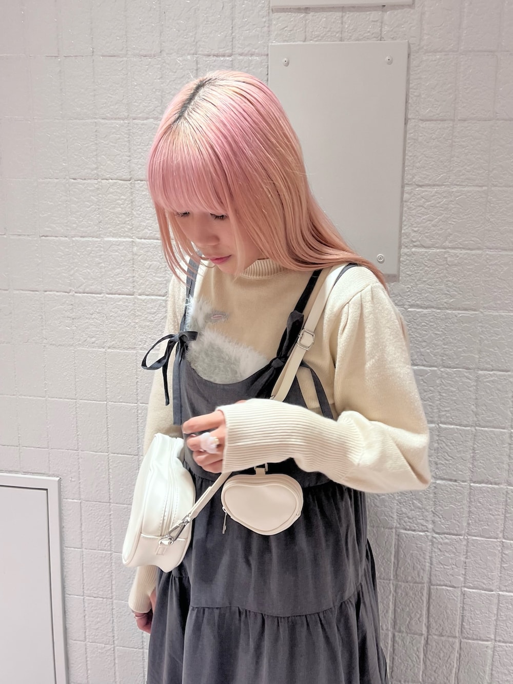 ホワイト系のニット/セーター、グレー系のワンピース、ホワイト系のハンドバッグを着用したレディースの秋コーディネートの5枚目の写真