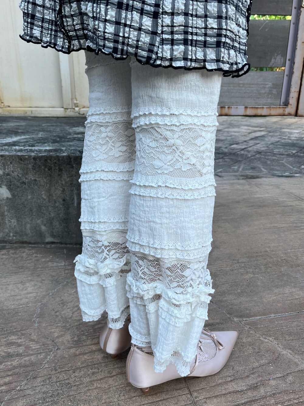 パープル系のニット/セーター、ブラック系のワンピース、ホワイト系のスラックスを着用したレディースの春コーディネートの5枚目の写真