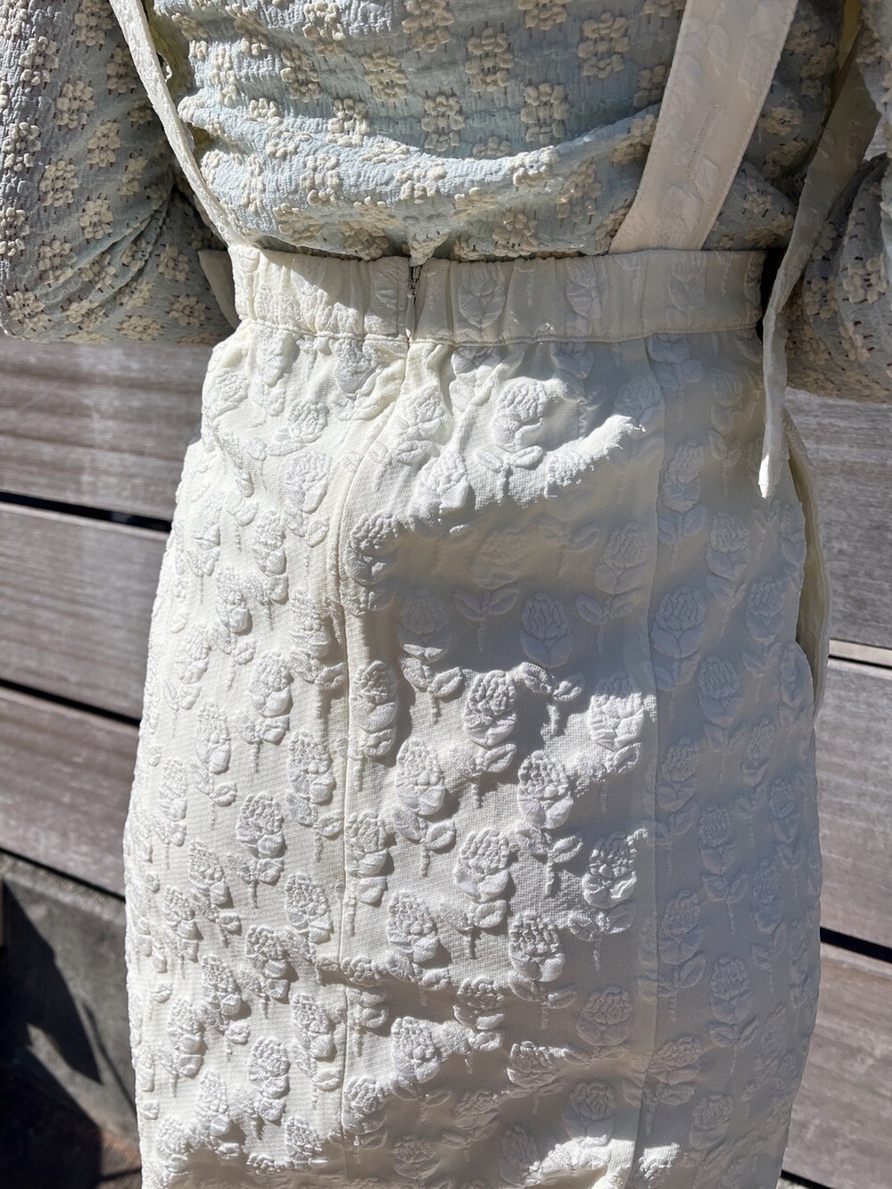 ブルー系のTシャツ/カットソー、ホワイト系のスカート、ホワイト系のパンプスを着用したレディースの冬コーディネートの6枚目の写真