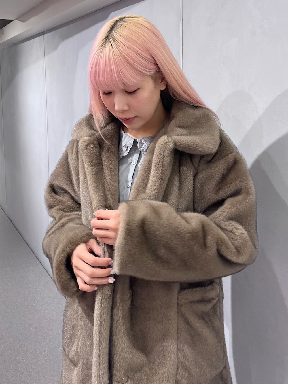 ブラウン系のノーカラーコート、グレー系のワンピース、ブルー系のデニムパンツを着用したレディースの冬コーディネートの5枚目の写真