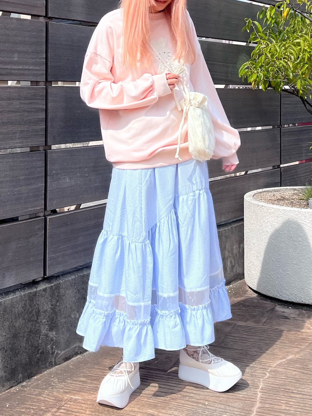 ピンク系のスウェット、ブルー系のスカート、ホワイト系のバレエシューズを着用したレディースの春コーディネートの2枚目の写真