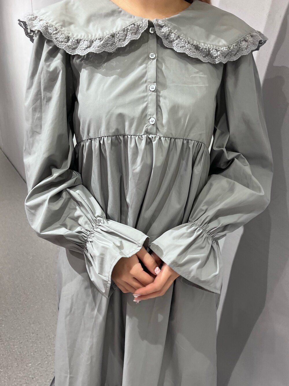 ブラウン系のノーカラーコート、グレー系のワンピース、ブルー系のデニムパンツを着用したレディースの冬コーディネートの9枚目の写真