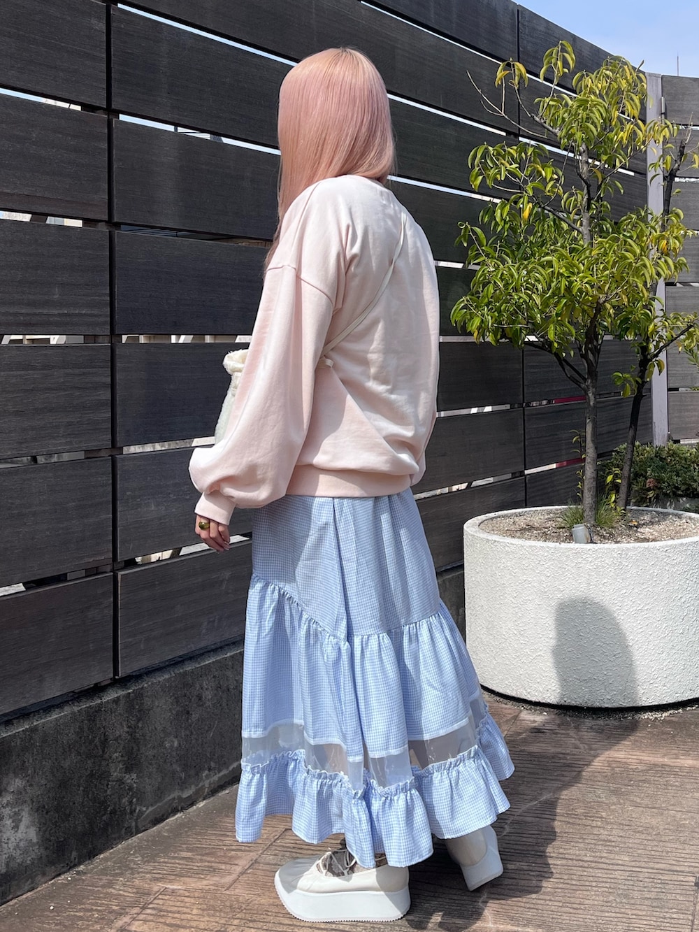 ピンク系のスウェット、ブルー系のスカート、ホワイト系のバレエシューズを着用したレディースの春コーディネートの3枚目の写真