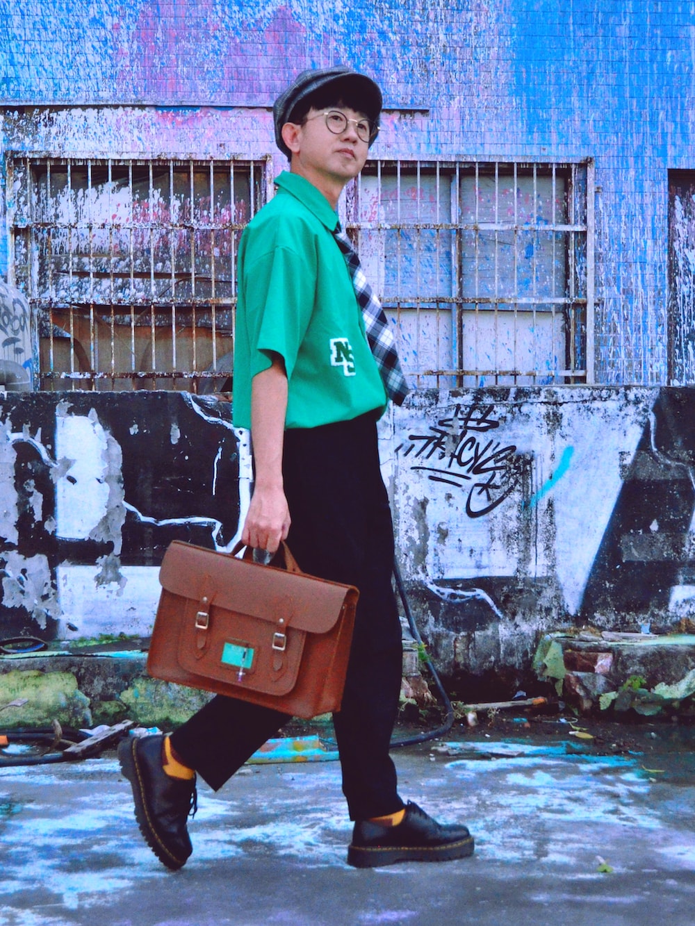 グレー系のチェスターコート、ブラック系のその他シューズ、ブラウン系のバックパック/リュックを着用したメンズの冬コーディネートの2枚目の写真