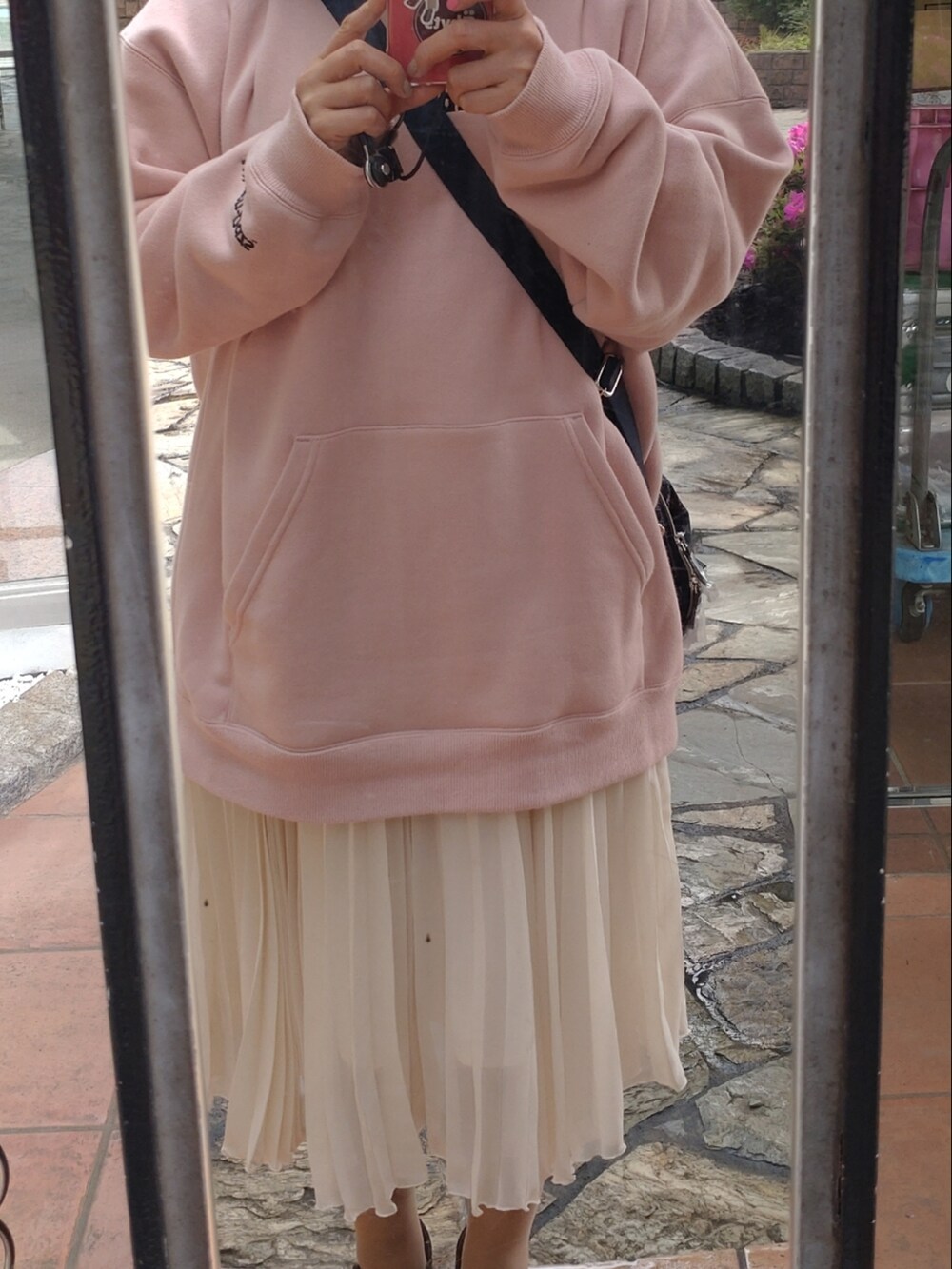 ピンク系のパーカー、ホワイト系のスカート、ブルー系のショルダーバッグを着用したレディースの冬コーディネートの2枚目の写真