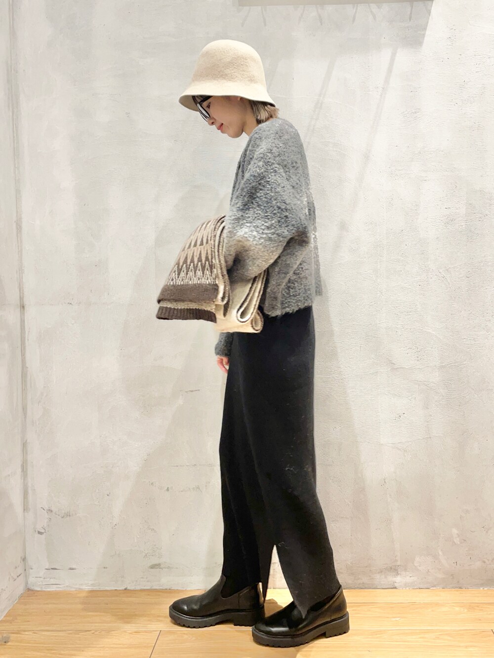 ブラック系のワンピース、ブラック系のブーツ、ベージュ系のハットを着用したレディースの冬コーディネートの2枚目の写真