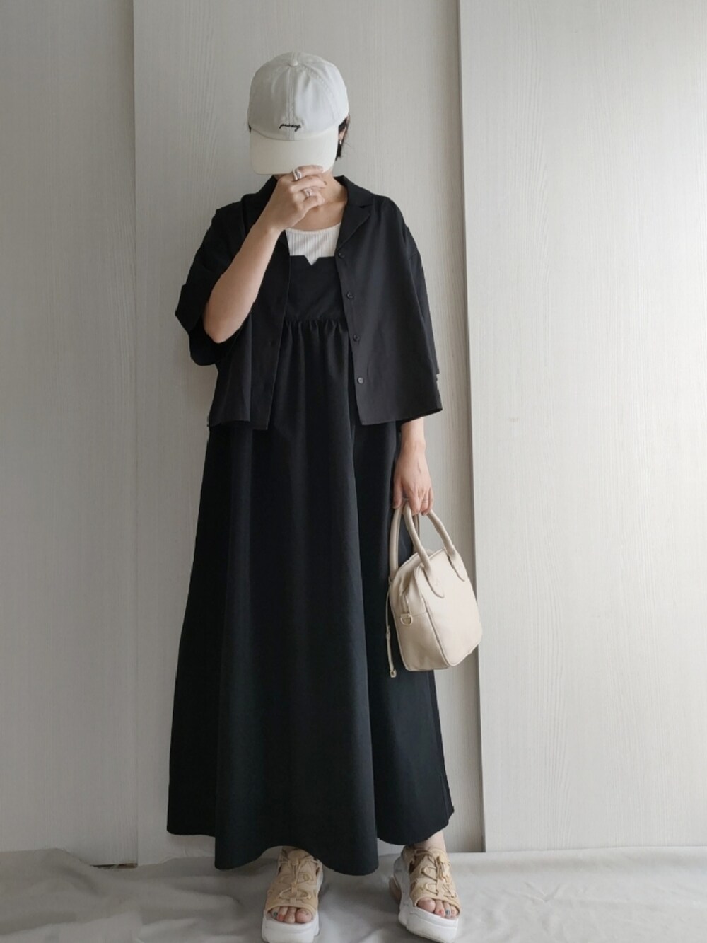 ブラック系のワンピース、ベージュ系のサンダル、ブラック系のシャツ/ブラウスを着用したレディースの春コーディネートの2枚目の写真