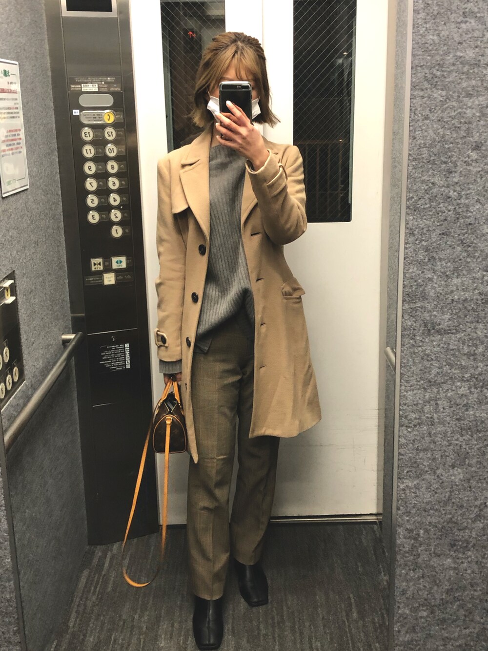 ベージュ系のトレンチコートを着用したレディースの冬コーディネートの3枚目の写真