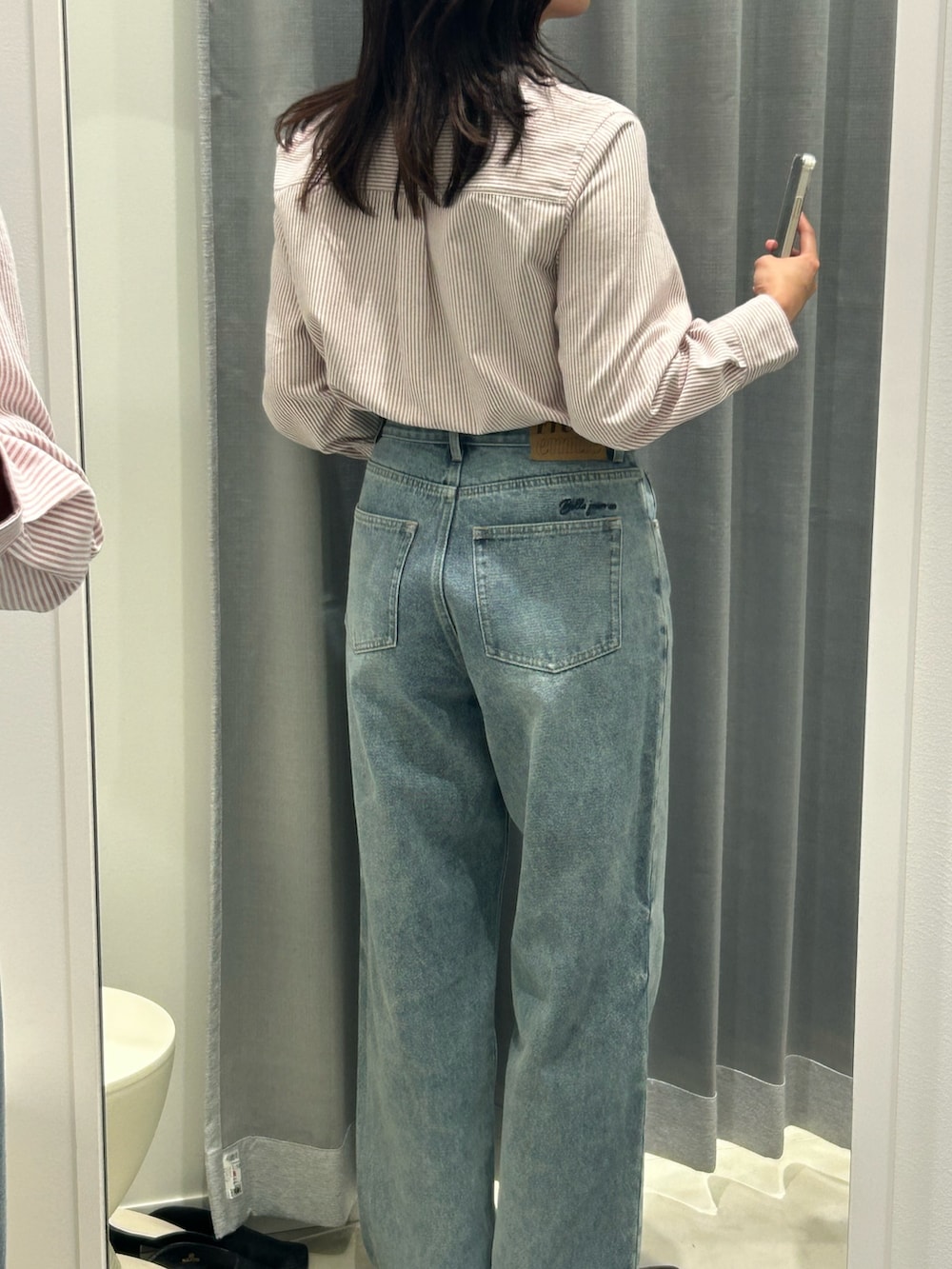 レッド系のシャツ/ブラウス、ブルー系のデニムパンツ、ブラウン系のボストンバッグを着用したレディースの秋コーディネートの6枚目の写真