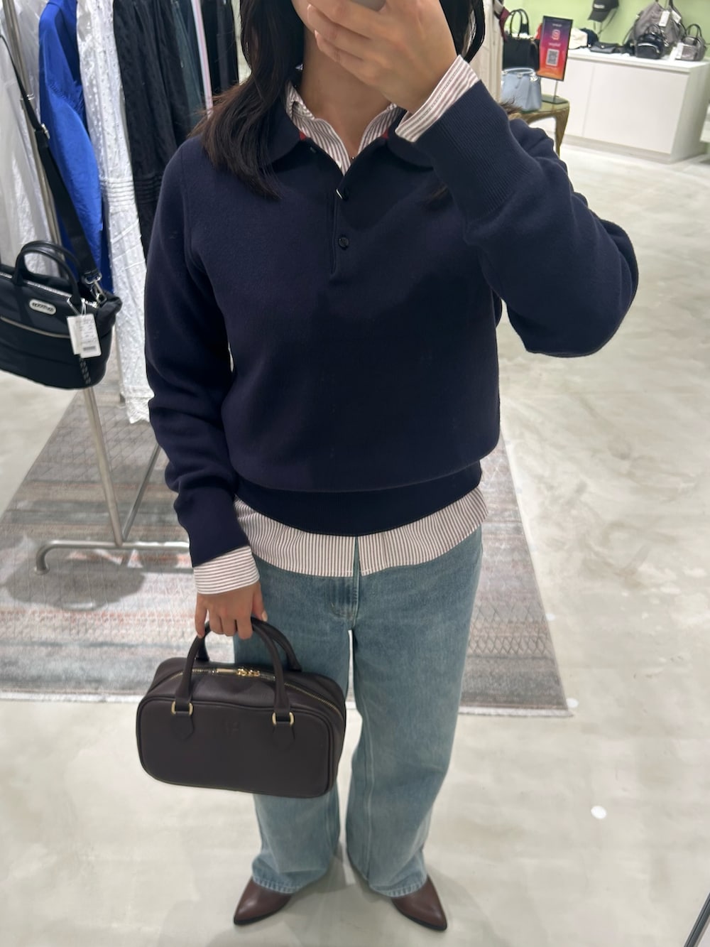 レッド系のシャツ/ブラウス、ブルー系のデニムパンツ、ブラウン系のボストンバッグを着用したレディースの秋コーディネートの3枚目の写真