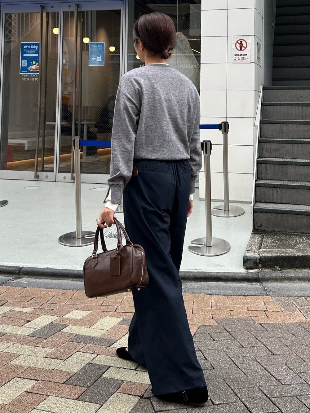 ブルー系のスラックス、ブラウン系のハンドバッグ、グレー系のカーディガン/ボレロを着用したレディースの秋コーディネートの2枚目の写真