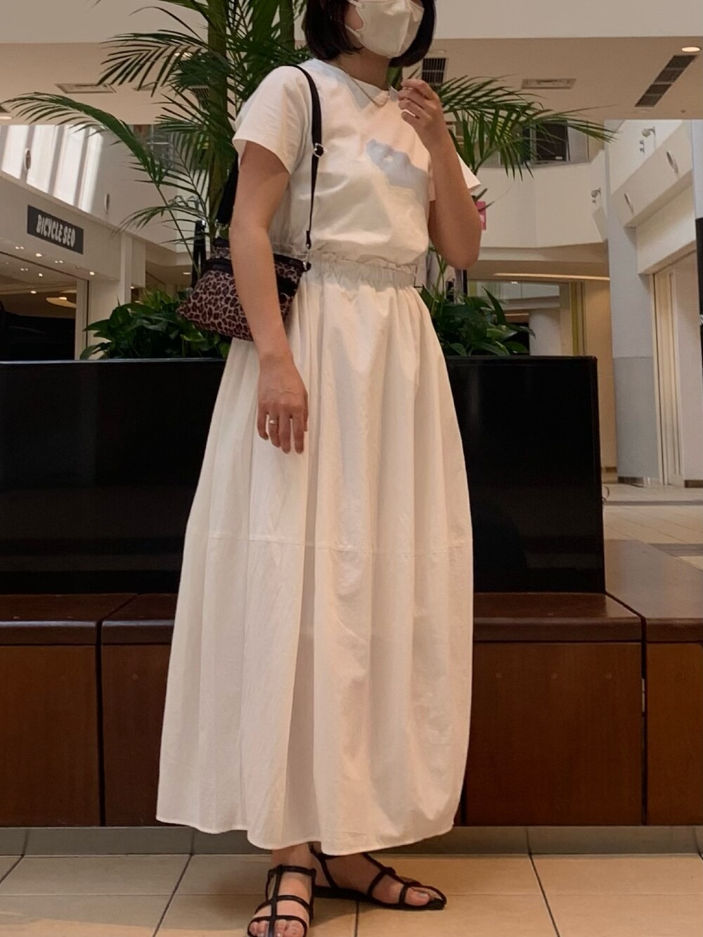 ホワイト系のワンピース、ブラック系のサンダル、ゴールド系のネックレスを着用したレディースの春コーディネートの2枚目の写真