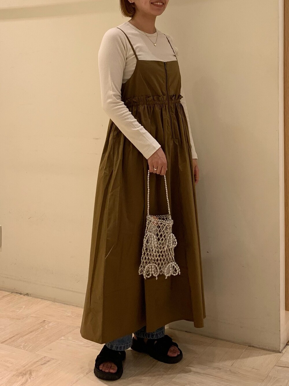 イエロー系のワンピース、ホワイト系のTシャツ/カットソー、ブルー系のデニムパンツを着用したレディースの秋コーディネートの2枚目の写真