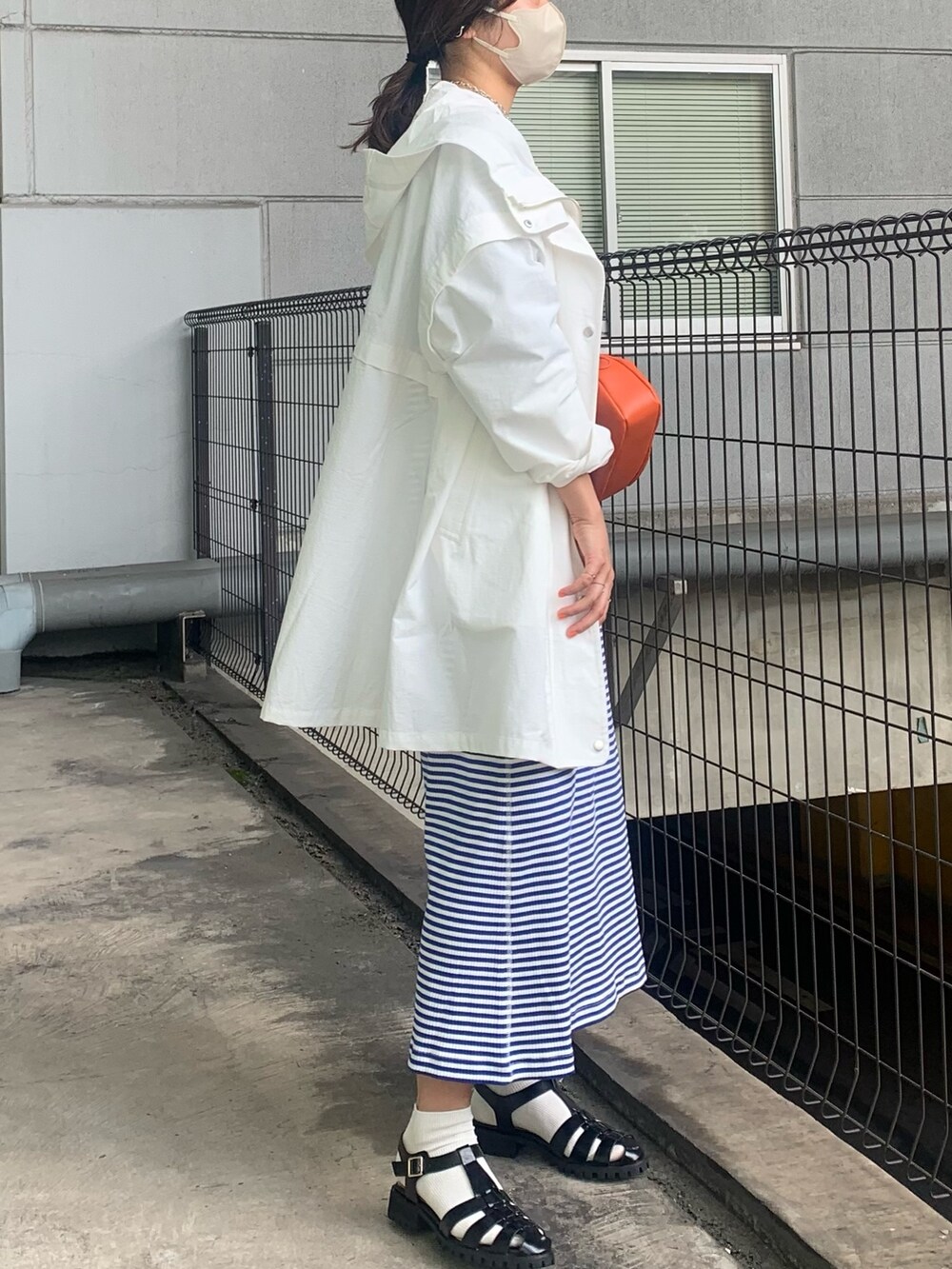 ホワイト系のブルゾン、ブルー系のワンピース、ブラック系のサンダルを着用したレディースの春コーディネートの3枚目の写真