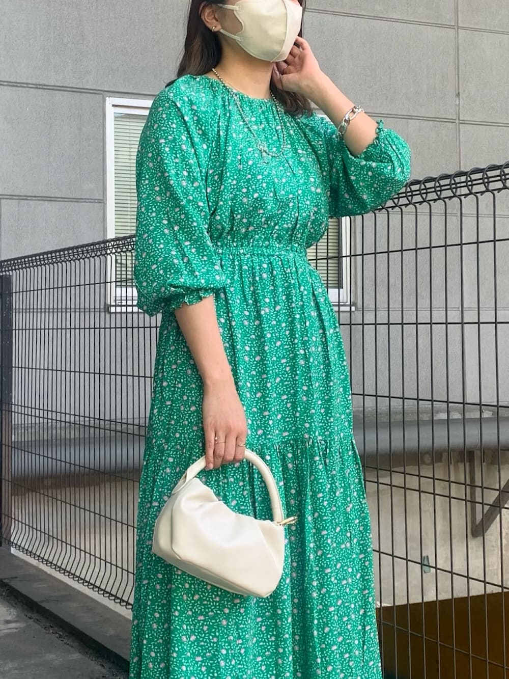 グリーン系のワンピース、ブルー系のデニムパンツ、ホワイト系のトートバッグを着用したレディースの春コーディネートの2枚目の写真