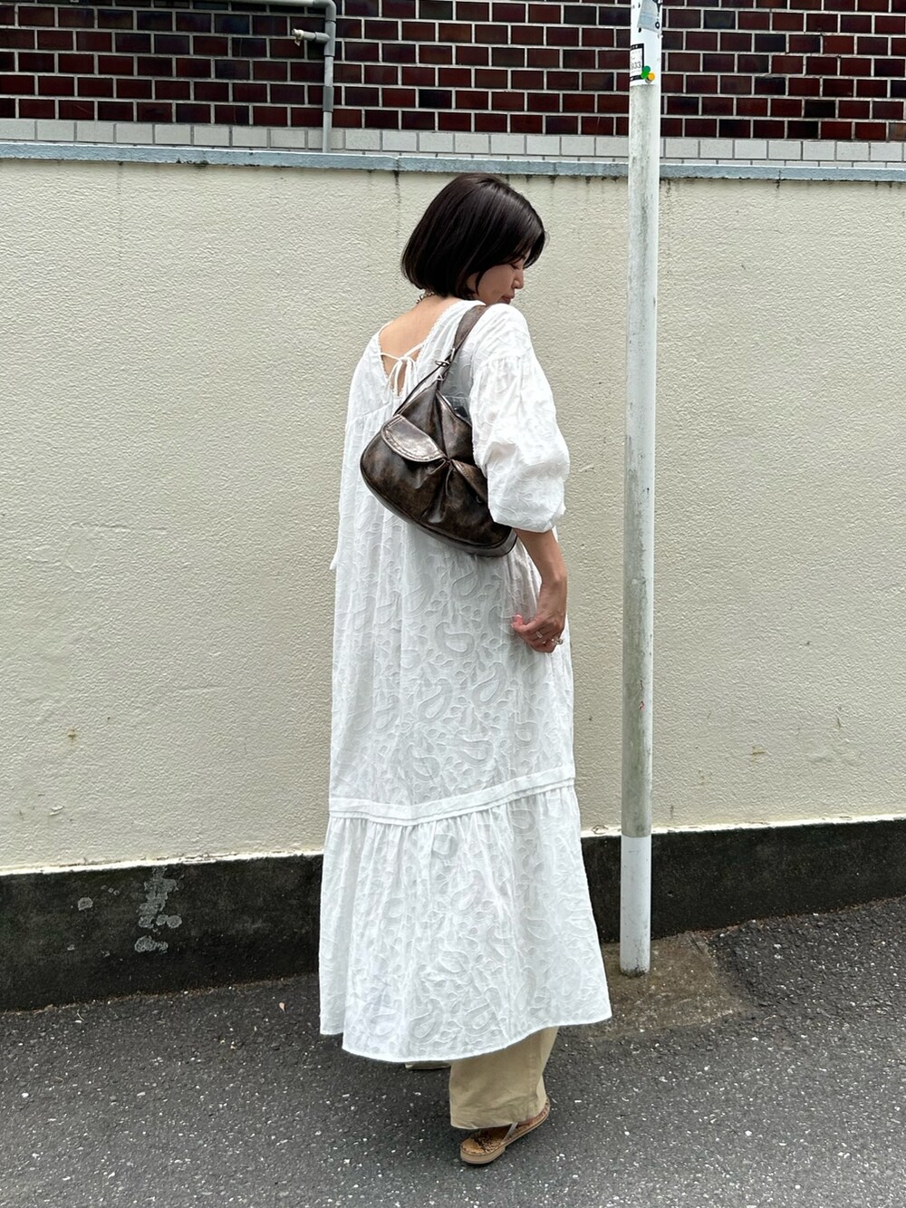 ホワイト系のワンピース、ベージュ系のチノパンツを着用したレディースの夏コーディネートの4枚目の写真