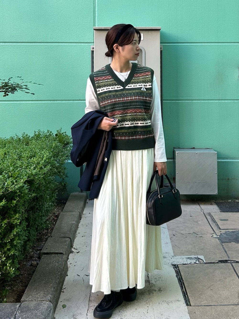 ブルー系のテーラードジャケット、グリーン系のベスト、ホワイト系のTシャツ/カットソーを着用したレディースの秋コーディネートの3枚目の写真