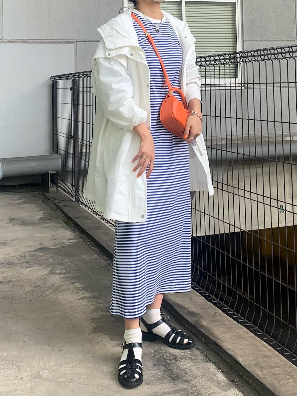 ホワイト系のブルゾン、ブルー系のワンピース、ブラック系のサンダルを着用したレディースの春コーディネートの2枚目の写真