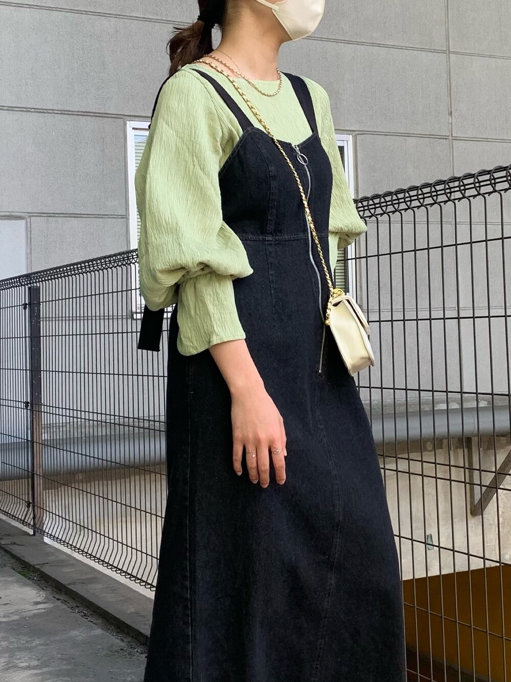 ブラック系のジャンパースカート、ベージュ系のトレンチコート、グリーン系のシャツ/ブラウスを着用したレディースの春コーディネートの3枚目の写真