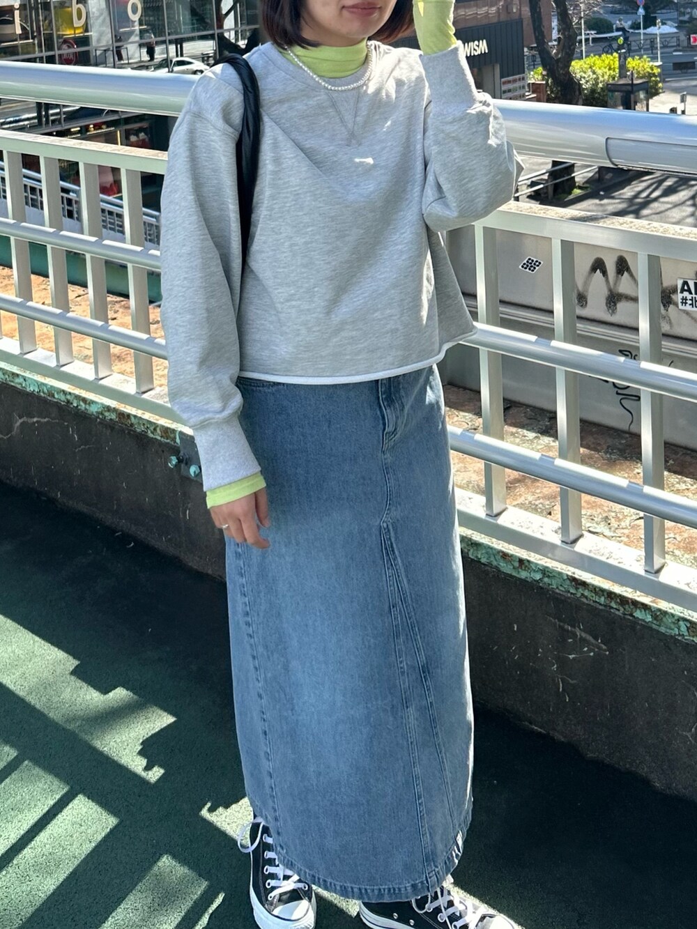 グレー系のスウェット、イエロー系のTシャツ/カットソー、ブルー系のデニムスカートを着用したレディースの冬コーディネートの3枚目の写真