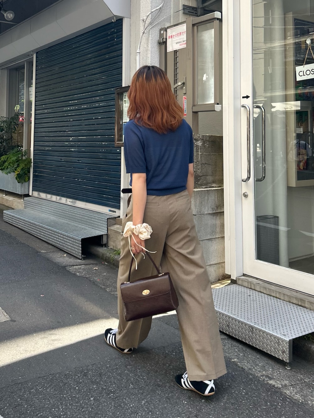 ブルー系のニット/セーター、イエロー系のスラックス、ブラウン系のショルダーバッグを着用したレディースの夏コーディネートの4枚目の写真