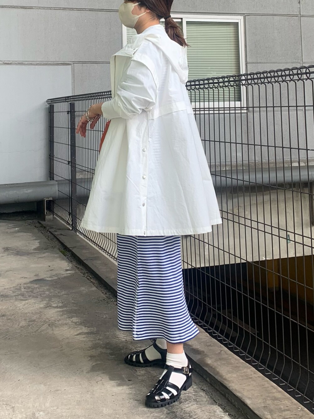 ホワイト系のブルゾン、ブルー系のワンピース、ブラック系のサンダルを着用したレディースの春コーディネートの4枚目の写真