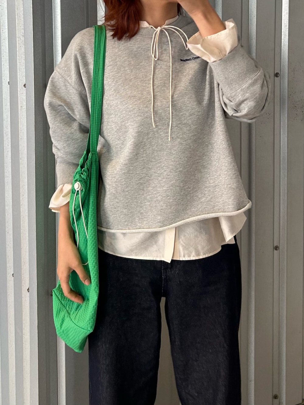 グレー系のスウェット、ホワイト系のシャツ/ブラウス、ブルー系のデニムパンツを着用したレディースの春コーディネートの2枚目の写真