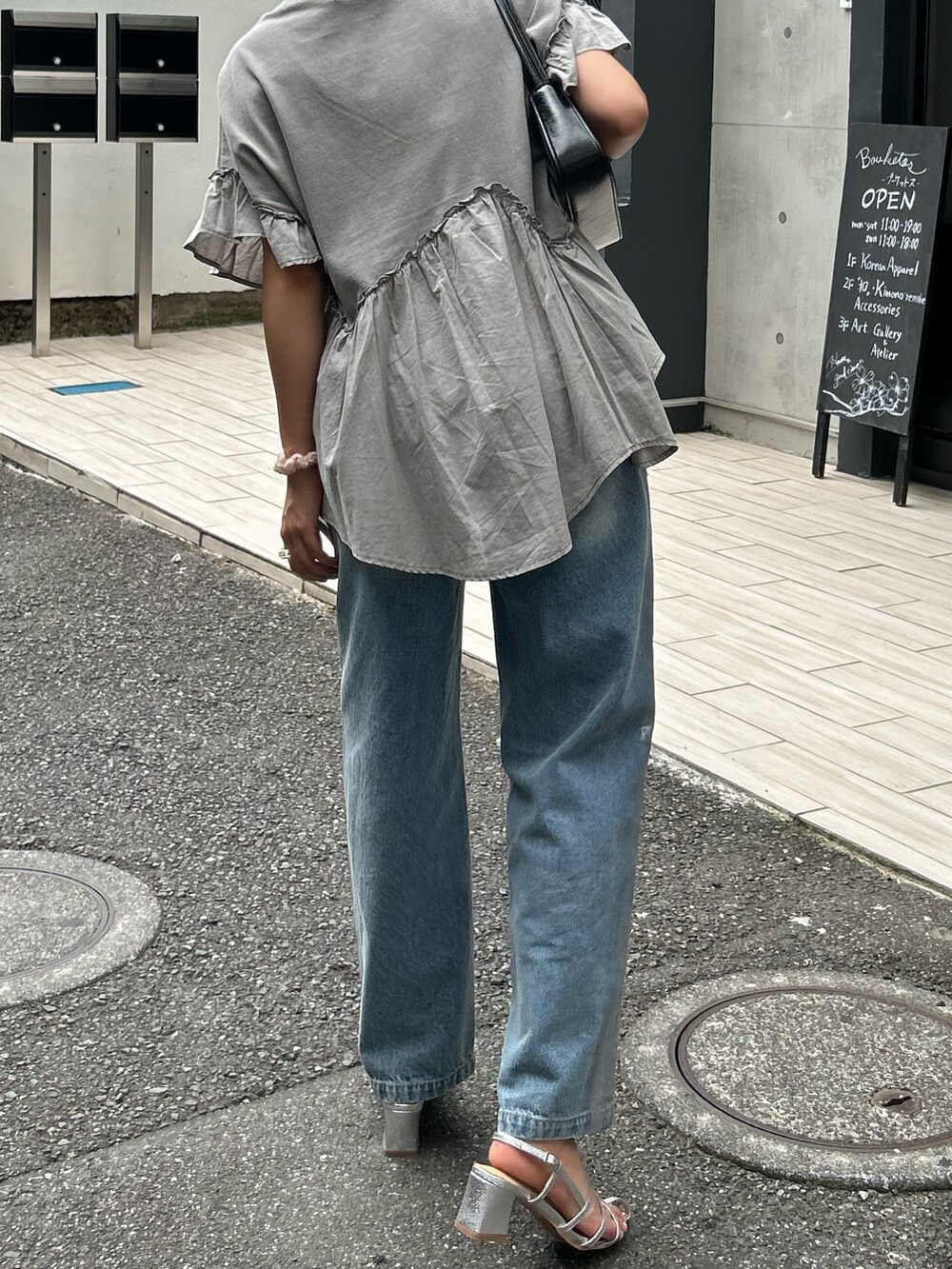 グレー系のTシャツ/カットソー、ブラック系のハンドバッグ、シルバー系のサンダルを着用したレディースの夏コーディネートの3枚目の写真