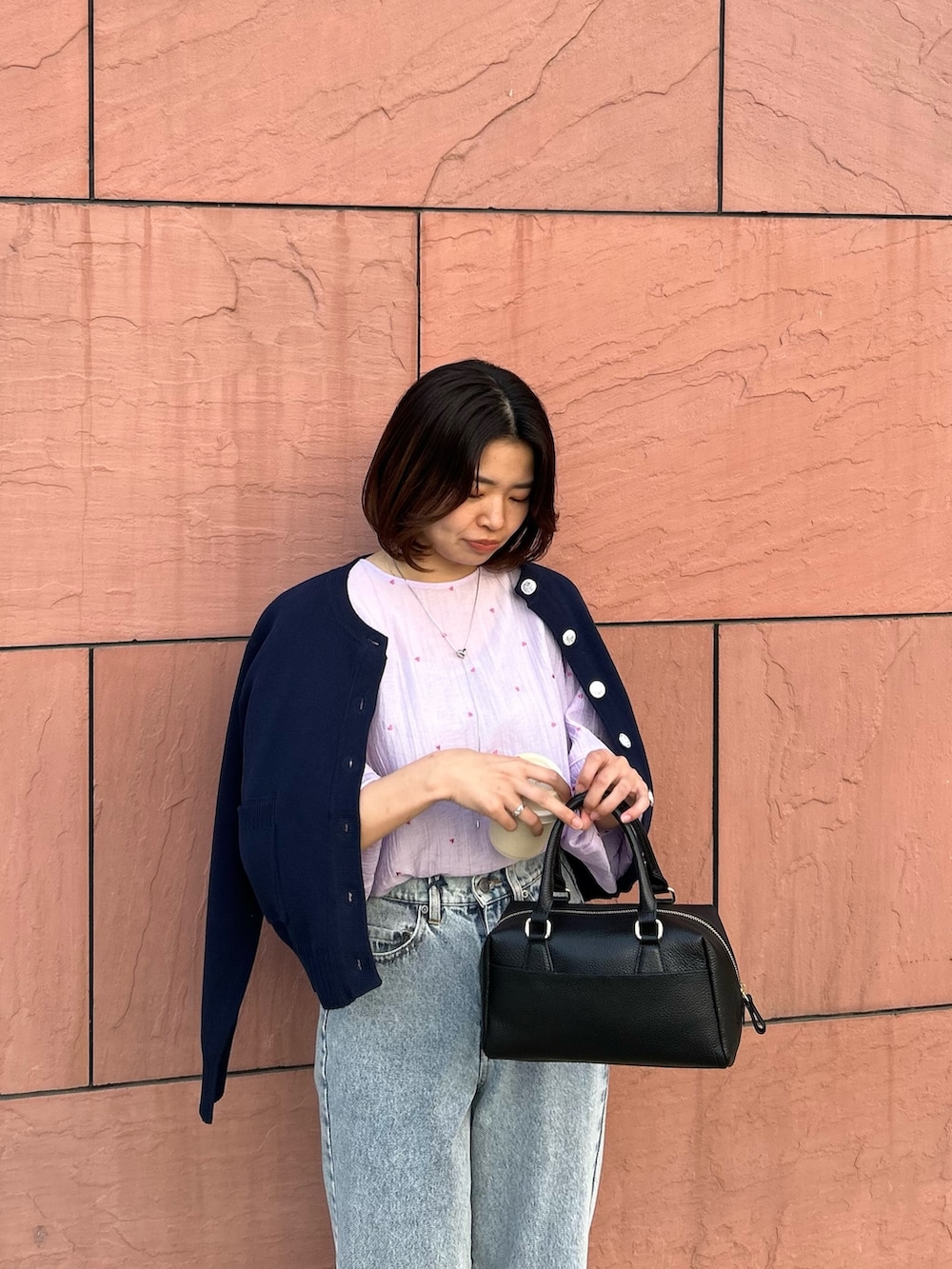 パープル系のシャツ/ブラウス、ブルー系のカーディガン/ボレロ、ブラック系のボストンバッグを着用したレディースの春コーディネートの2枚目の写真