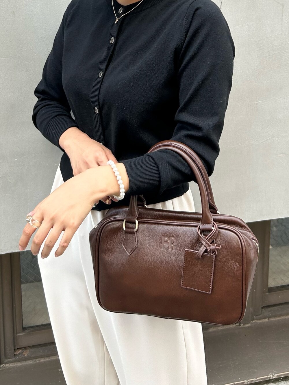 ホワイト系のその他パンツ、ブラウン系のハンドバッグ、ブラック系のニット/セーターを着用したレディースの秋コーディネートの3枚目の写真