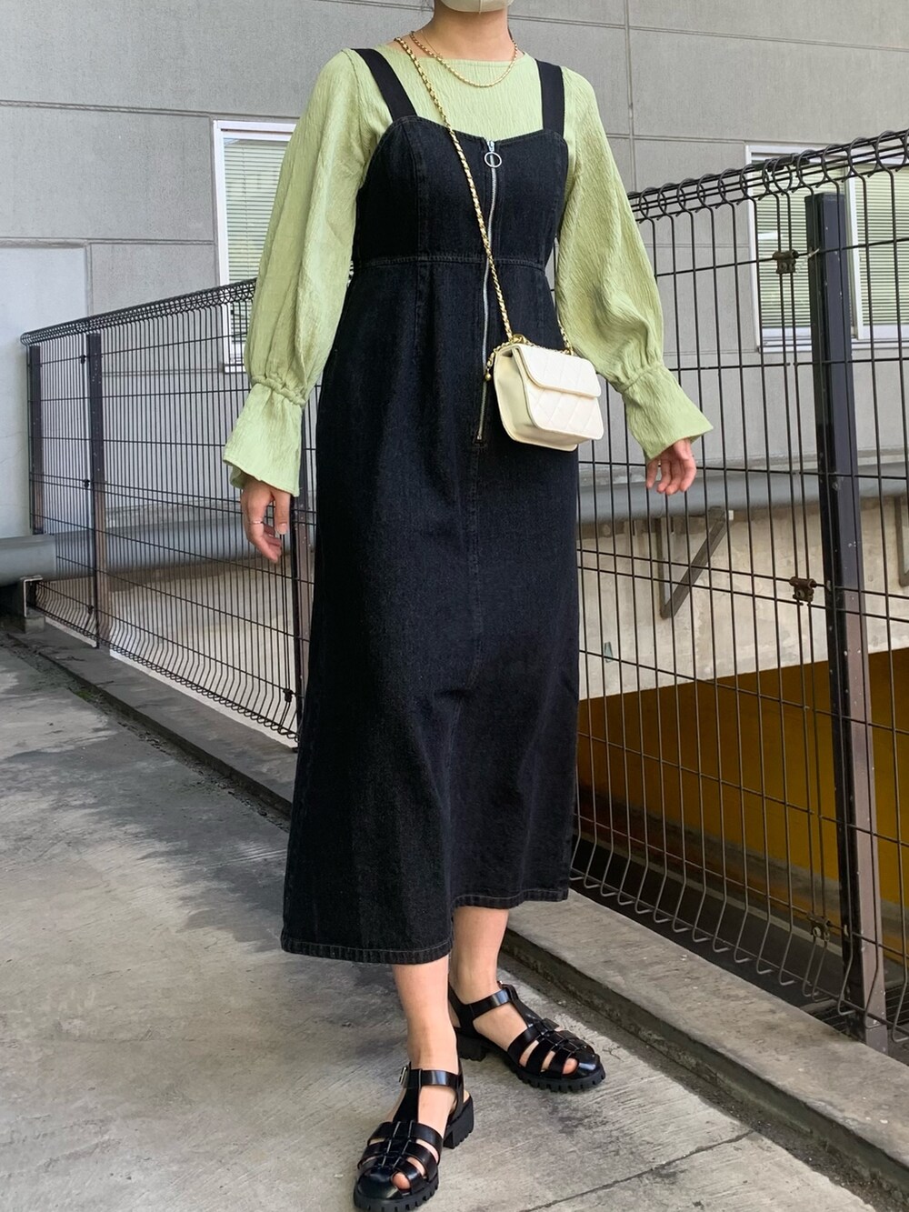 ブラック系のジャンパースカート、ベージュ系のトレンチコート、グリーン系のシャツ/ブラウスを着用したレディースの春コーディネートの4枚目の写真