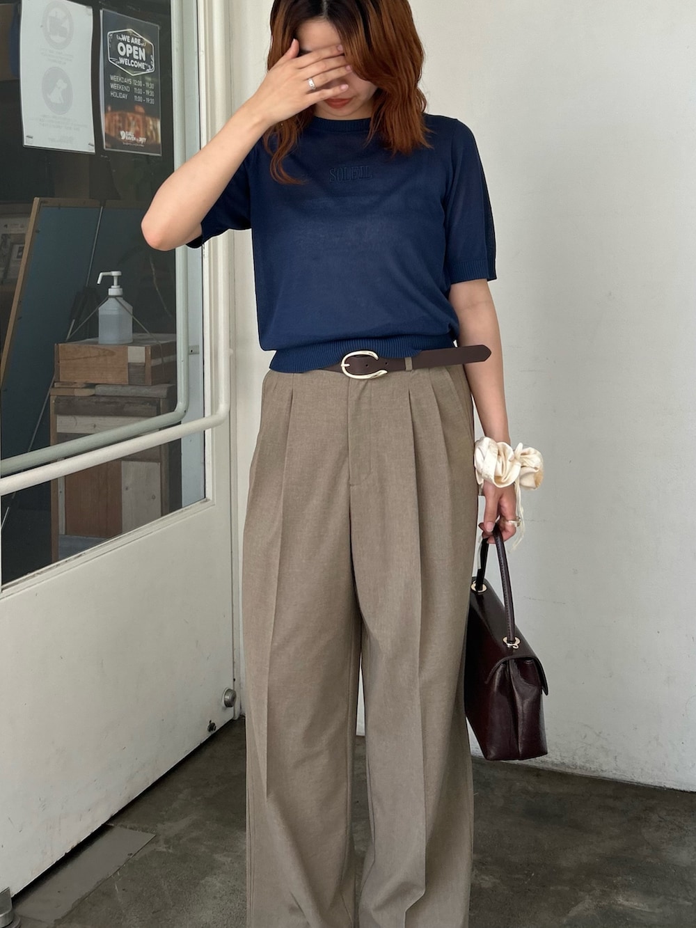 ブルー系のニット/セーター、イエロー系のスラックス、ブラウン系のショルダーバッグを着用したレディースの夏コーディネートの5枚目の写真