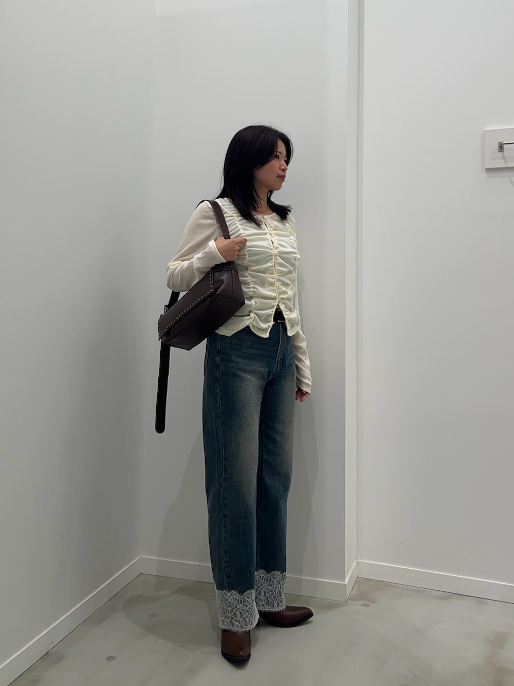 ホワイト系のカーディガン/ボレロ、ブルー系のデニムパンツ、ブラウン系のショルダーバッグを着用したレディースの秋コーディネートの3枚目の写真