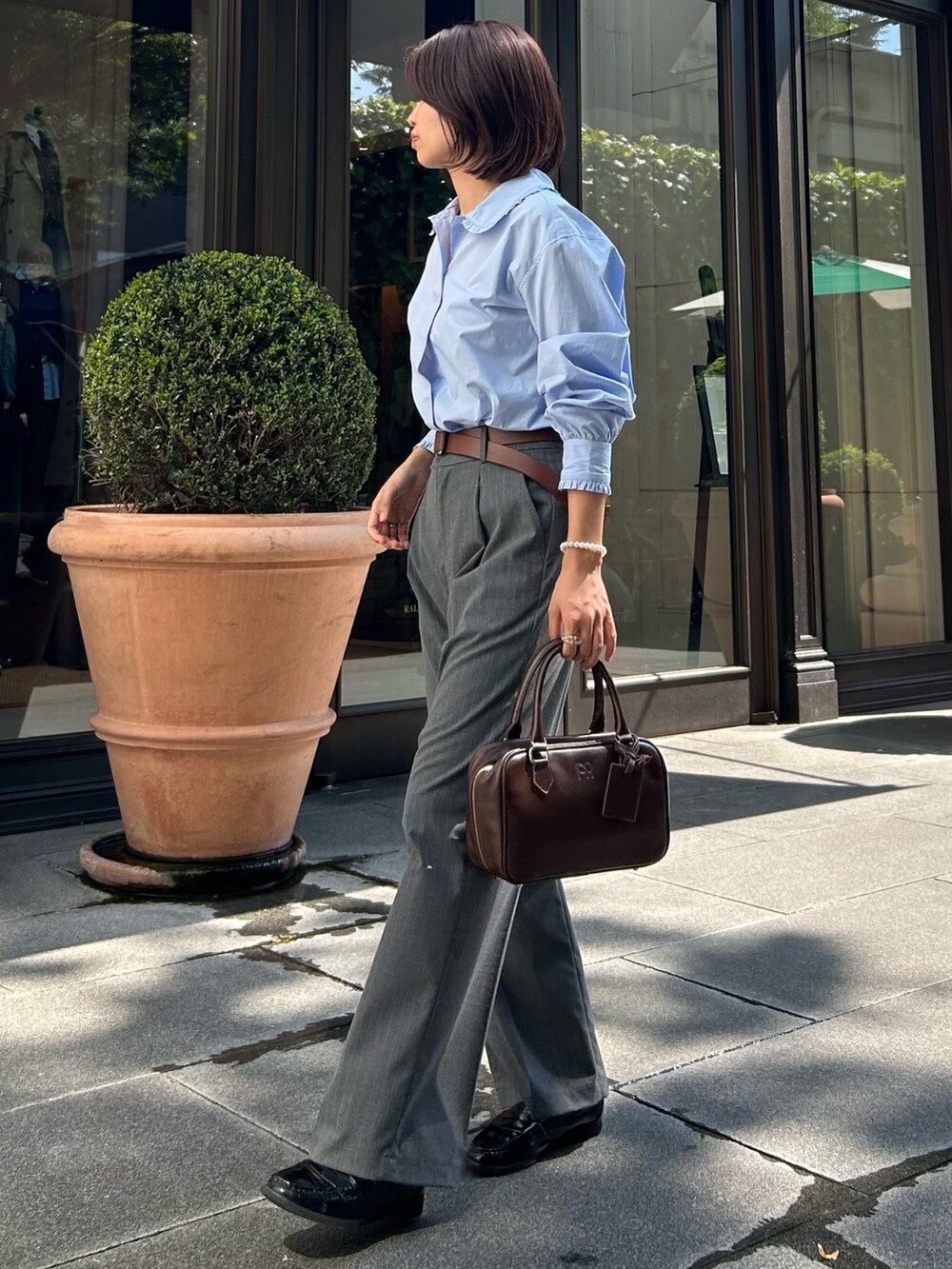 グレー系のスラックス、ブルー系のシャツ/ブラウス、ブラウン系のハンドバッグを着用したレディースの秋コーディネートの3枚目の写真