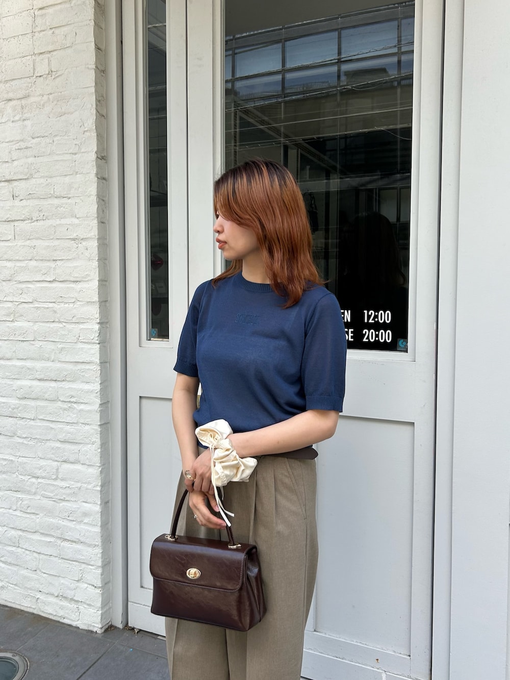 ブルー系のニット/セーター、イエロー系のスラックス、ブラウン系のショルダーバッグを着用したレディースの夏コーディネートの2枚目の写真