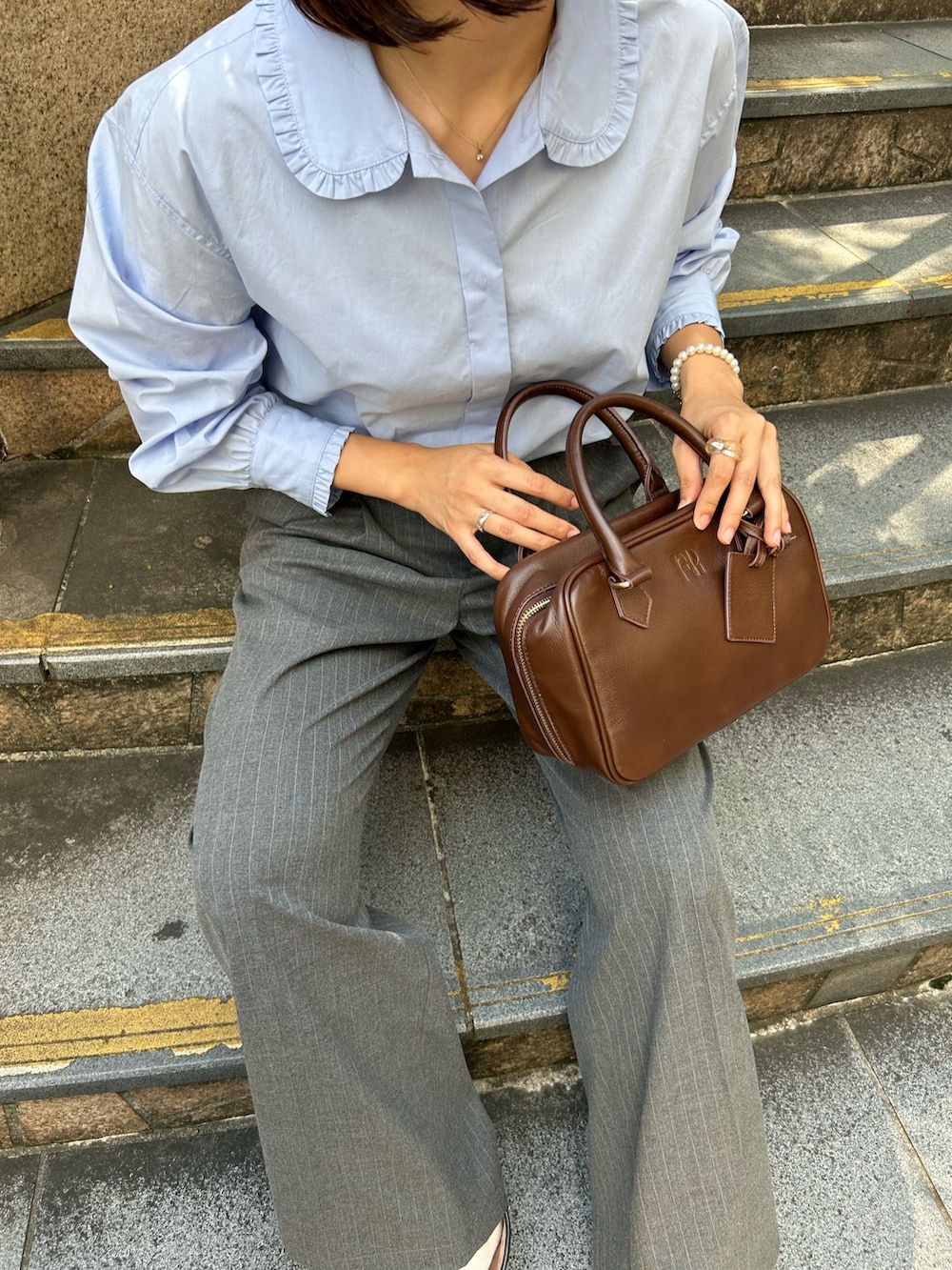 グレー系のスラックス、ブルー系のシャツ/ブラウス、ブラウン系のハンドバッグを着用したレディースの秋コーディネートの4枚目の写真